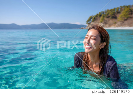 エメラルドグリーンの海で笑顔を見せる日本人女性と田舎の自然風景 126149170
