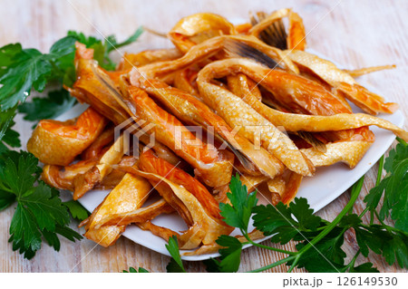 Smoked salmon belly strips on plate on wooden table 126149530