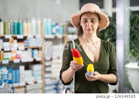 Middle-aged woman choosing repellent in chemist's shop Middle-aged woman choosing repellent in chemist's shop 126149583