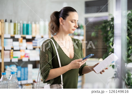 Woman scans on mobile qr code cream in pharmacy 126149616