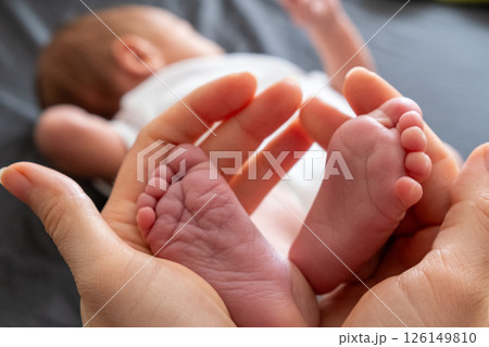 Tender Moment: Adult Hands Holding Newborn Baby Feet Tender Moment: Adult Hands Holding Newborn Baby Feet 126149810