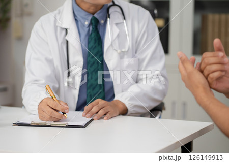 Male doctor consulting patient filling form at consultation, talking to patient filling signing medical paper at appointment visit in clinic. 126149913
