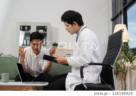 Concerned male patient, patient talks with healthcare professional and signing medical paper at appointment visit in clinic. Concerned male patient, patient talks with healthcare professional and signing medical paper at appointment visit in clinic. 126149929