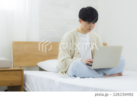 ベッドでノートパソコンを操作する男性 126150492