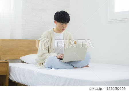ベッドでノートパソコンを操作する男性 126150493