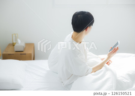 ベッドでスマートフォンを使う男性 ベッドでスマートフォンを使う男性 126150521