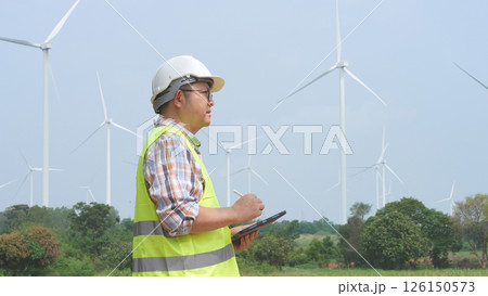 Engineer working with laptop at wind turbine field generating electricity for renewable clean energy 126150573