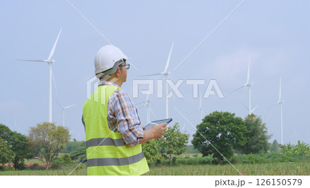 Engineer working with laptop at wind turbine field generating electricity for renewable clean energy Engineer working with laptop at wind turbine field generating electricity for renewable clean energy 126150579