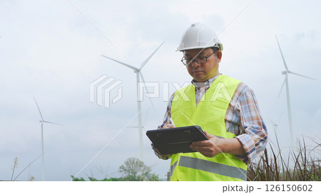 Engineer working with laptop at wind turbine field generating electricity for renewable clean energy 126150602