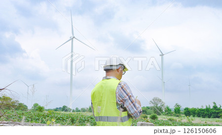 Engineer working with laptop at wind turbine field generating electricity for renewable clean energy 126150606