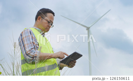 Engineer working with laptop at wind turbine field generating electricity for renewable clean energy Engineer working with laptop at wind turbine field generating electricity for renewable clean energy 126150611