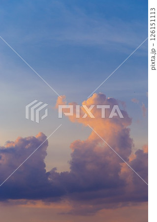 Towering cumulus clouds glowing in golden sunlight against clear blue sky at sunset with dramatic natural cloudscape and atmospheric light. High quality photo 126151113