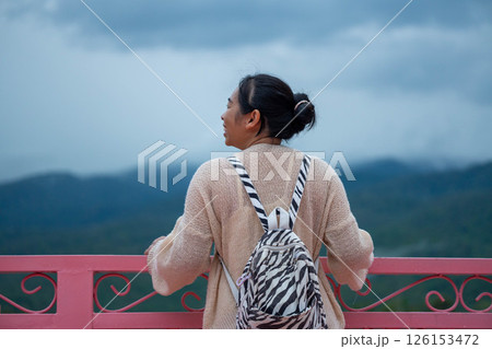 Young female tourist is enjoying the beautiful natural scenery with fog at the national park. Young female tourist is enjoying the beautiful natural scenery with fog at the national park. 126153472