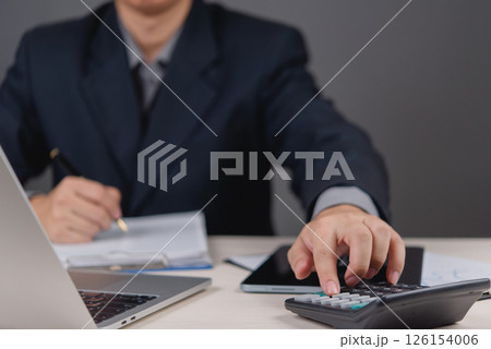 businessman working using a calculator and reviewing financial documents. accounting, financial analysis, budget planning, and business tax, finance management, and strategy investment planning. businessman working using a calculator and reviewing financial documents. accounting, financial analysis, budget planning, and business tax, finance management, and strategy investment planning. 126154006