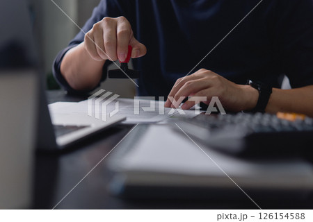 A business professional stamping an official document in an office environment, symbolizing document approval and business paperwork processes. 126154588