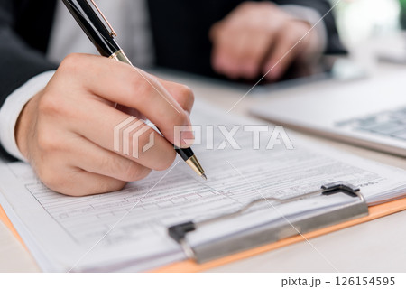 Business and financial paperwork verification featuring a close-up of hands working on a contract. Ideal for corporate, investment, and legal consulting. 126154595