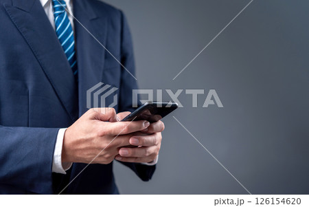 businessman using a smartphone for digital communication in a modern professional setting. The image reflects mobile technology and business connectivity. 126154620