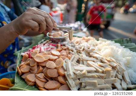 Woman seller hands portion sliced soy tofu into bowl for street food sale in Thailand, asian recipe Woman seller hands portion sliced soy tofu into bowl for street food sale in Thailand, asian recipe 126155260
