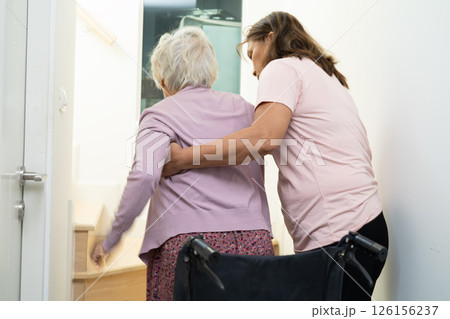 Caregiver help asian or elderly old woman sitting wheelchair support up the stairs in home. Caregiver help asian or elderly old woman sitting wheelchair support up the stairs in home. 126156237