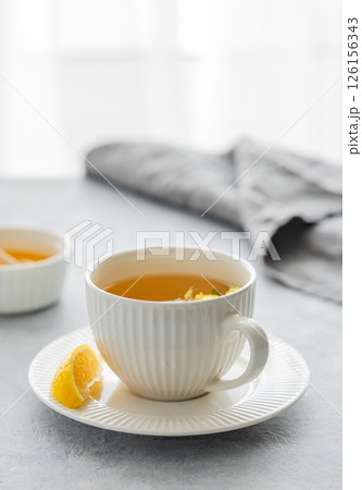 Cup of herbal tea with lemon and honey on table against window background 126156343