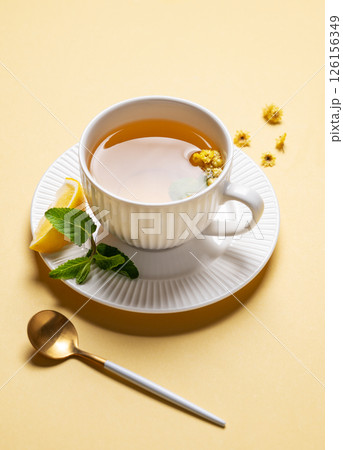 Cup of herbal tea with lemon, honey and mint on yellow background with morning shadows. Cup of herbal tea with lemon, honey and mint on yellow background with morning shadows. 126156349