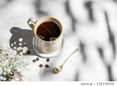 Cup of freshly brewed coffee and bouquet of gypsophila on light textured background Cup of freshly brewed coffee and bouquet of gypsophila on light textured background 126156358