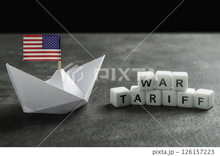 Paper boat with the USA flag and cubes with the text of war tariff on a black background. Concept of the United States of America versus China trade war disputes or economic conflict 126157223