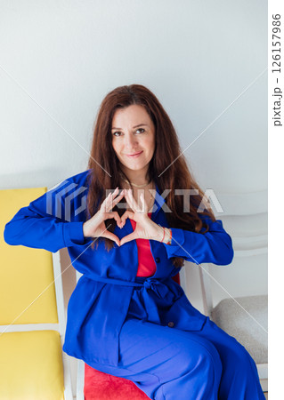 brunette woman in blue business suit showing her heart with her hands brunette woman in blue business suit showing her heart with her hands 126157986