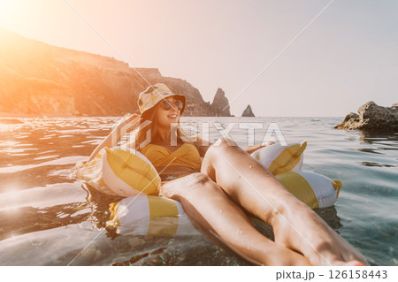 Woman, Beach, Float - Woman relaxing on an inflatable float in the clear blue water of a beach. Woman, Beach, Float - Woman relaxing on an inflatable float in the clear blue water of a beach. 126158443