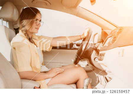 A woman in a yellow shirt is driving a car. She is wearing glasses and has her hands on the steering wheel A woman in a yellow shirt is driving a car. She is wearing glasses and has her hands on the steering wheel 126158457