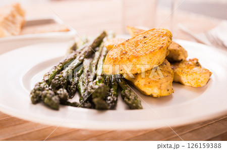 Cooked dish. Chicken nuggets with green asparagus on plate 126159388