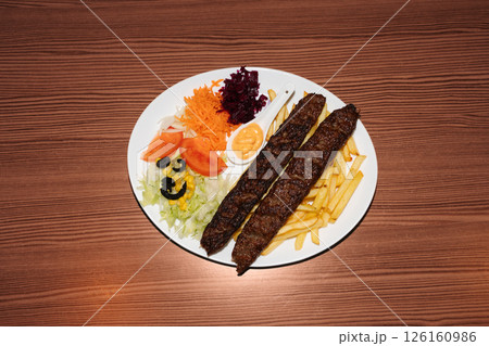 Turkish kebab plate with fries, vegetables and sausages. Delicious freshly prepared meal, perfect for menus, restaurants, or food delivery concepts. 126160986