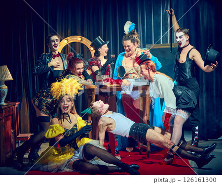 Cabaret performers act chaotic, funny scene, bending, laughing, posing dramatically on red carpet. 126161300