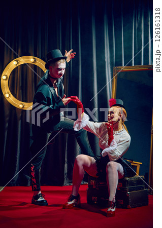 Elegant cabaret duo in top hats posing in smoke and spotlight on stage with romantic dramatic flair. 126161318