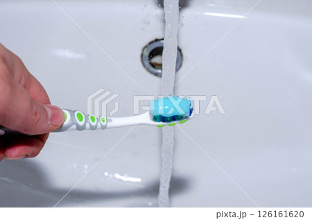 Toothbrush with Blue Gel Toothpaste Under Running Tap Water Oral Hygiene Concept 126161620