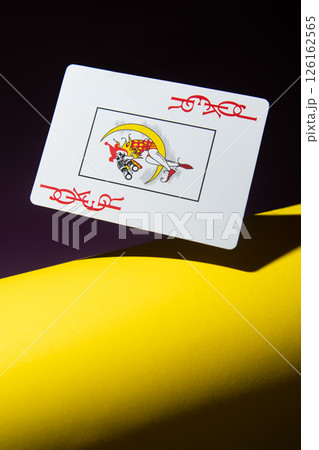 Joker card in flight on a yellow and black background. Joker card in flight on a yellow and black background. 126162565