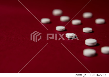 White pills on red background.  126162783