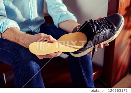 Elegant man holds a leather shoe and puts insole in it 126163171