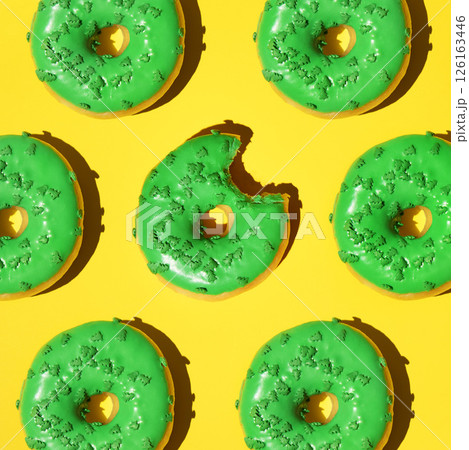 Pattern of green donuts on a yellow background. Square, studio photo. Pattern of green donuts on a yellow background. Square, studio photo. 126163446