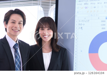 会議室のスクリーンの前に立つスーツ姿の男女 会議室のスクリーンの前に立つスーツ姿の男女 126164104