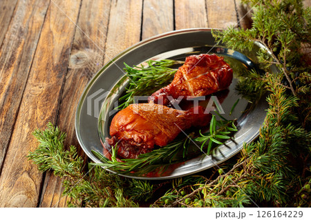 Smoked chicken drumsticks and juniper branches on a wooden table. Smoked chicken drumsticks and juniper branches on a wooden table. 126164229