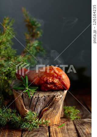 Smoked chicken drumstick and juniper branches on a wooden table. 126164235