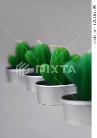 Small green candles in the shape of cacti stand diagonally on a gray background. Atmosphere of comfort. Decor in the room. 126165390