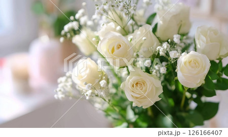 Fresh white roses arranged beautifully in a vase on a bright sunny day in a cozy indoor setting 126166407