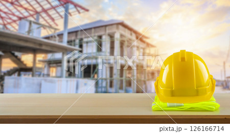 Yellow safety construction helmet on wood table with construction site background Yellow safety construction helmet on wood table with construction site background 126166714