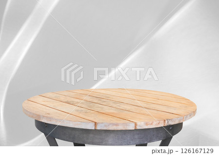 Round wood table top with abstract shadow drop on white wall background for mockup product display 126167129