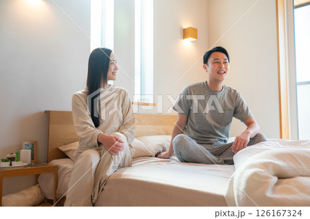 ベッドで座ってリラックスする日本人男女 ベッドで座ってリラックスする日本人男女 126167324