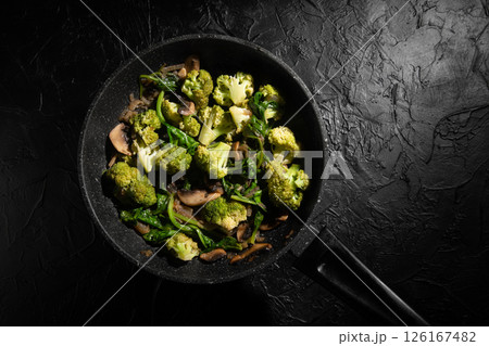 Dish Fried vegetables with mushrooms in a non-stick pan. Broccoli, spinach, onion in olive oil. Cooking healthy food. 126167482