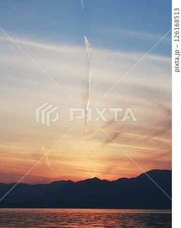湖に沈む夕日と立ち上る神秘的な雰囲気の雲 湖に沈む夕日と立ち上る神秘的な雰囲気の雲 126168513