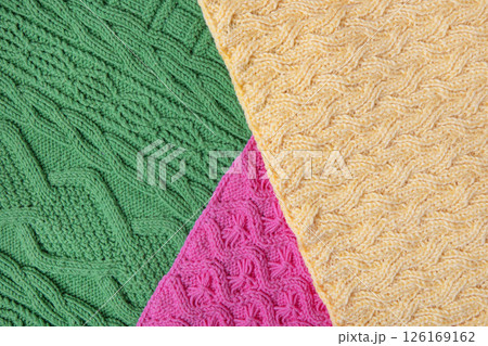 Abstract textural knitted green yellow and pink background. Large knitted fabric with a pattern. Close-up of a knitted blanket 126169162